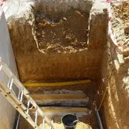 Travaux d'excavation pour la pose d'un monument funéraire dans un cimetière.