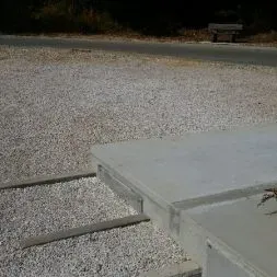 Allée gravillonnée et soubassement en béton d'un monument funéraire au cimetière.