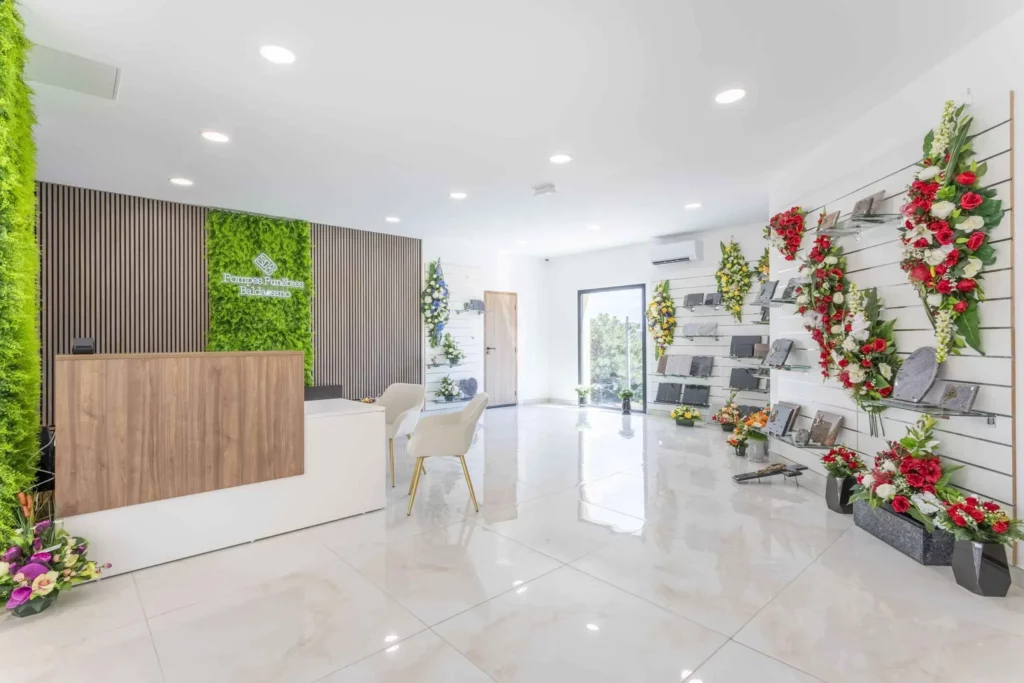 Intérieur de l'agence funéraire avec comptoir d'accueil et exposition de fleurs.