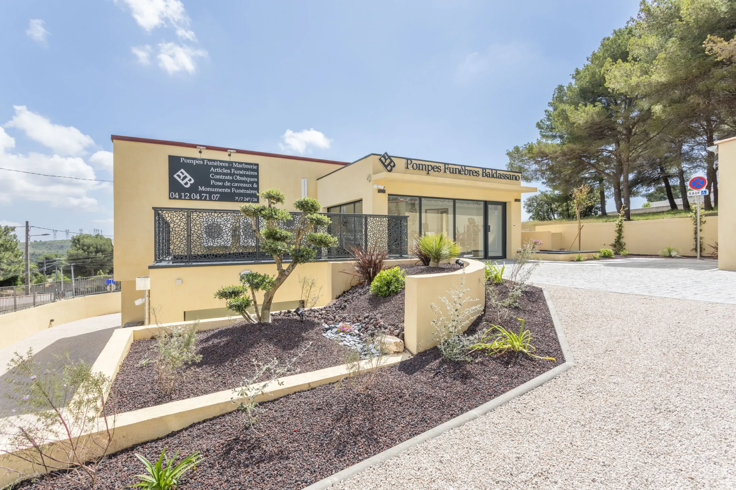 Façade moderne de l'agence de Pompes Funèbres Baldassano avec jardin paysager.