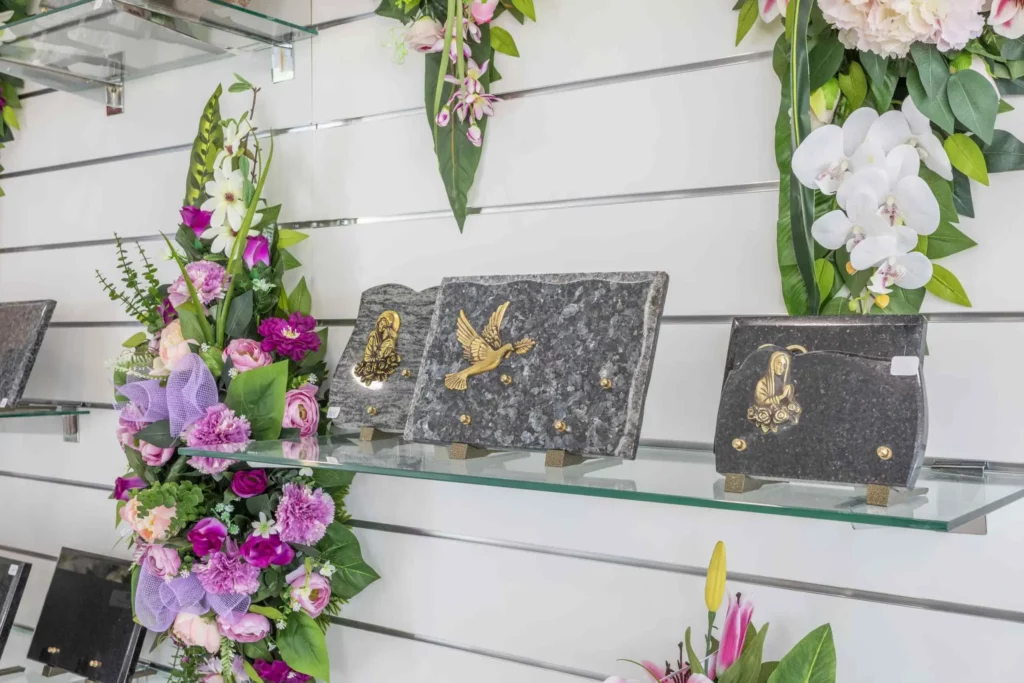 Exposition de plaques funéraires en granit et compositions de fleurs artificielles.